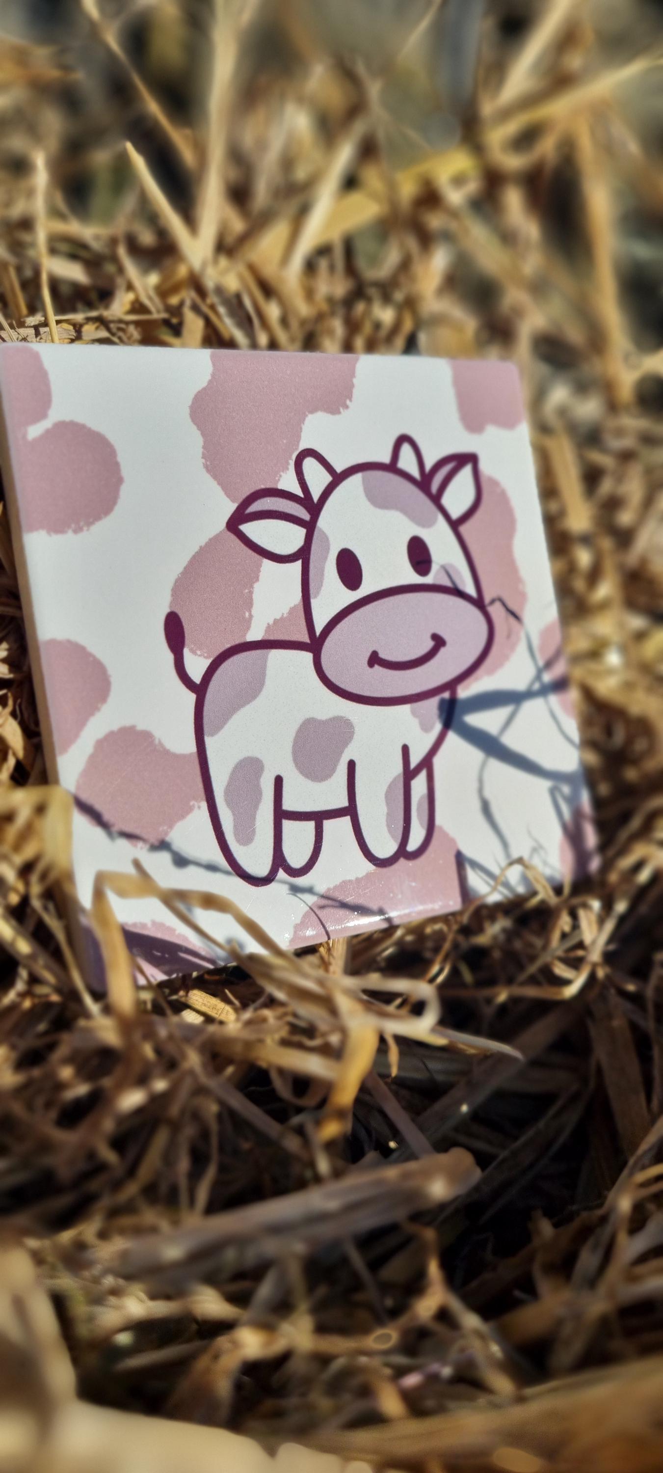 Cute cartoon cow design on an animal lover coaster placed on dry grass background