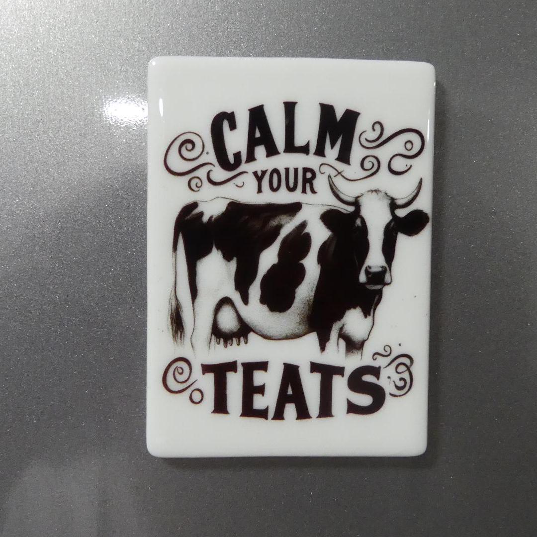 Calm your teats novelty magnet with black and white cow design on white rectangular background