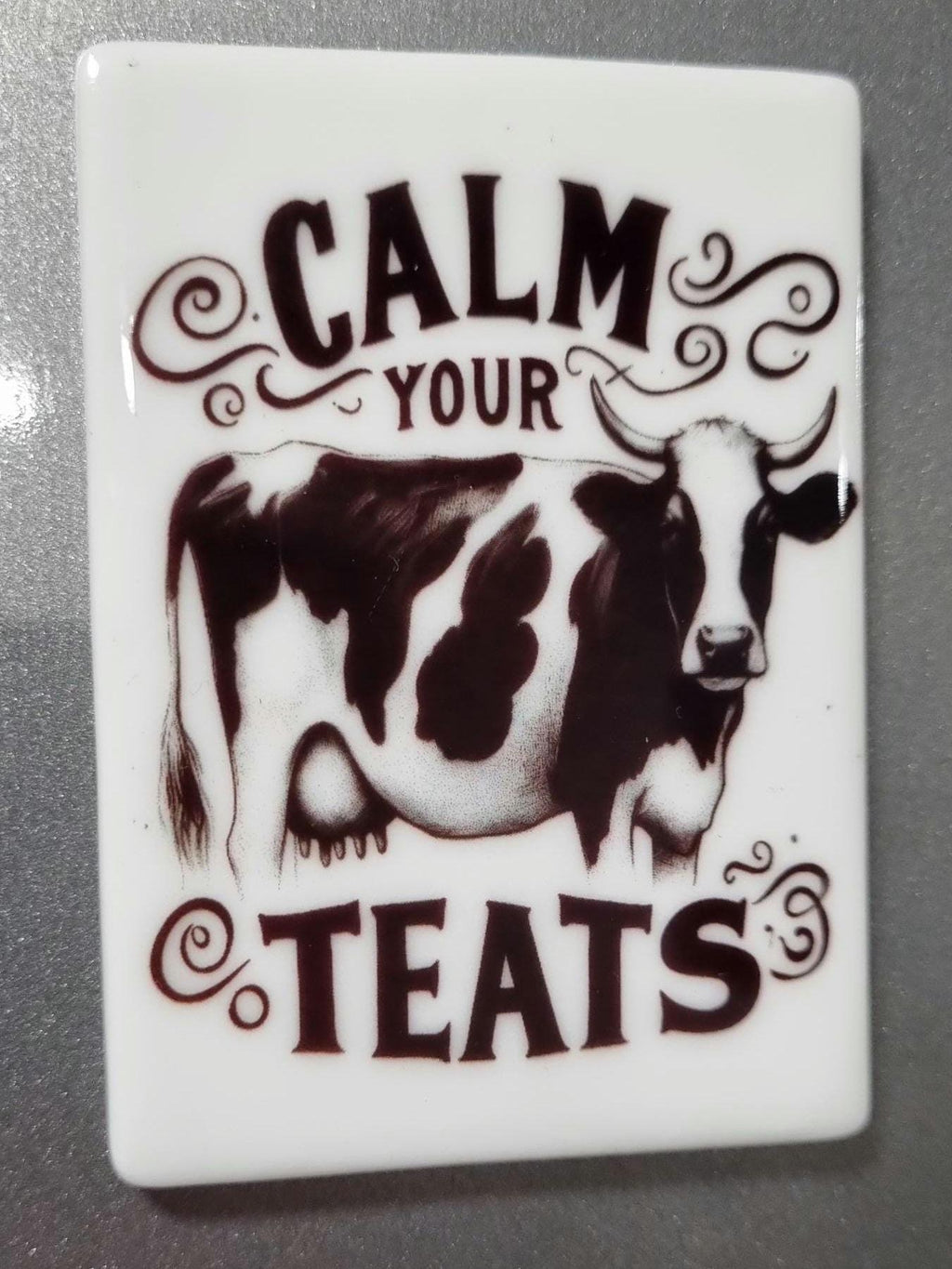 Calm your teats novelty magnet featuring a black and white cow illustration on white background