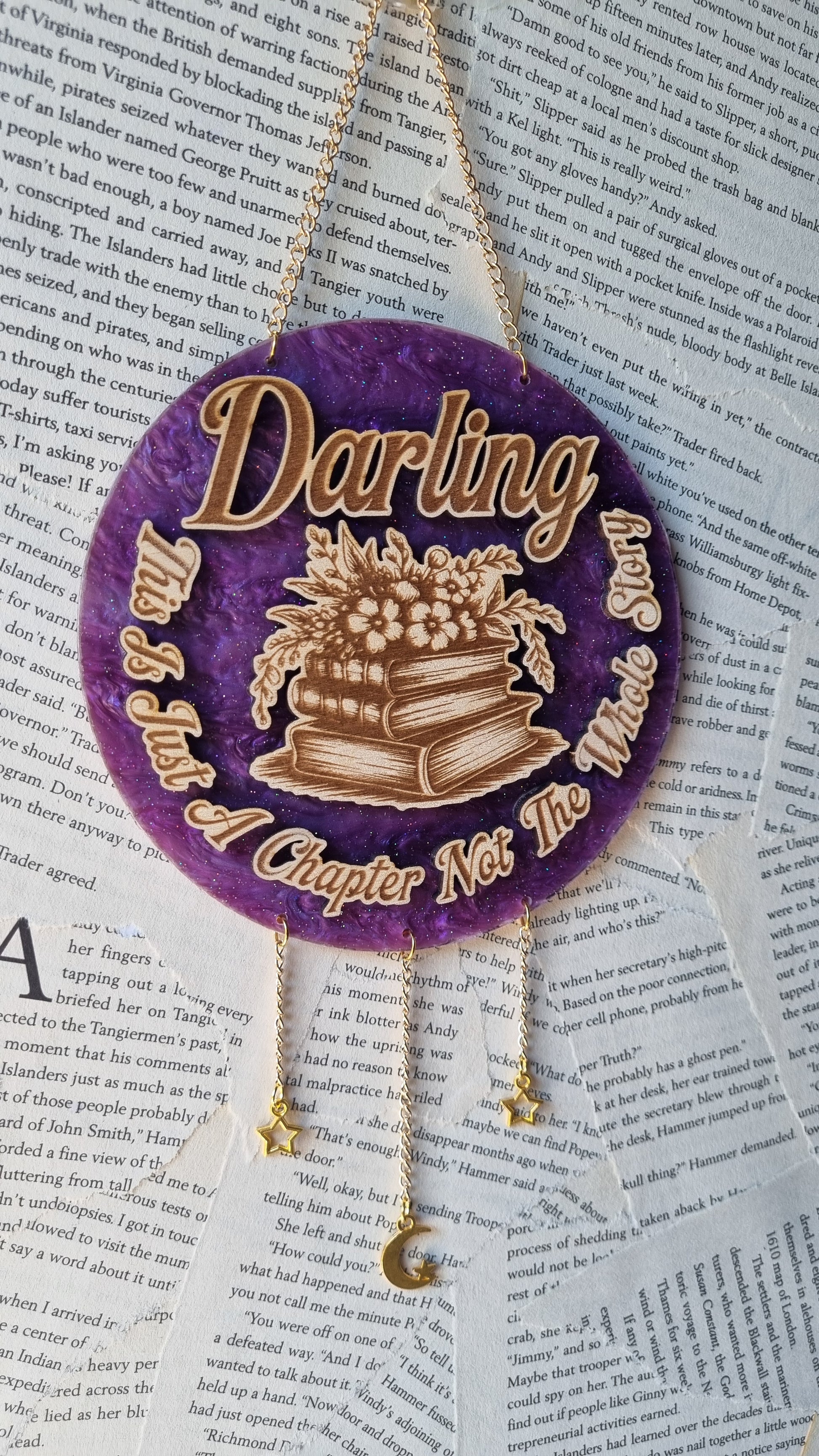 Purple round wood ornament with stack of books and text including just a chapter bookish ornament