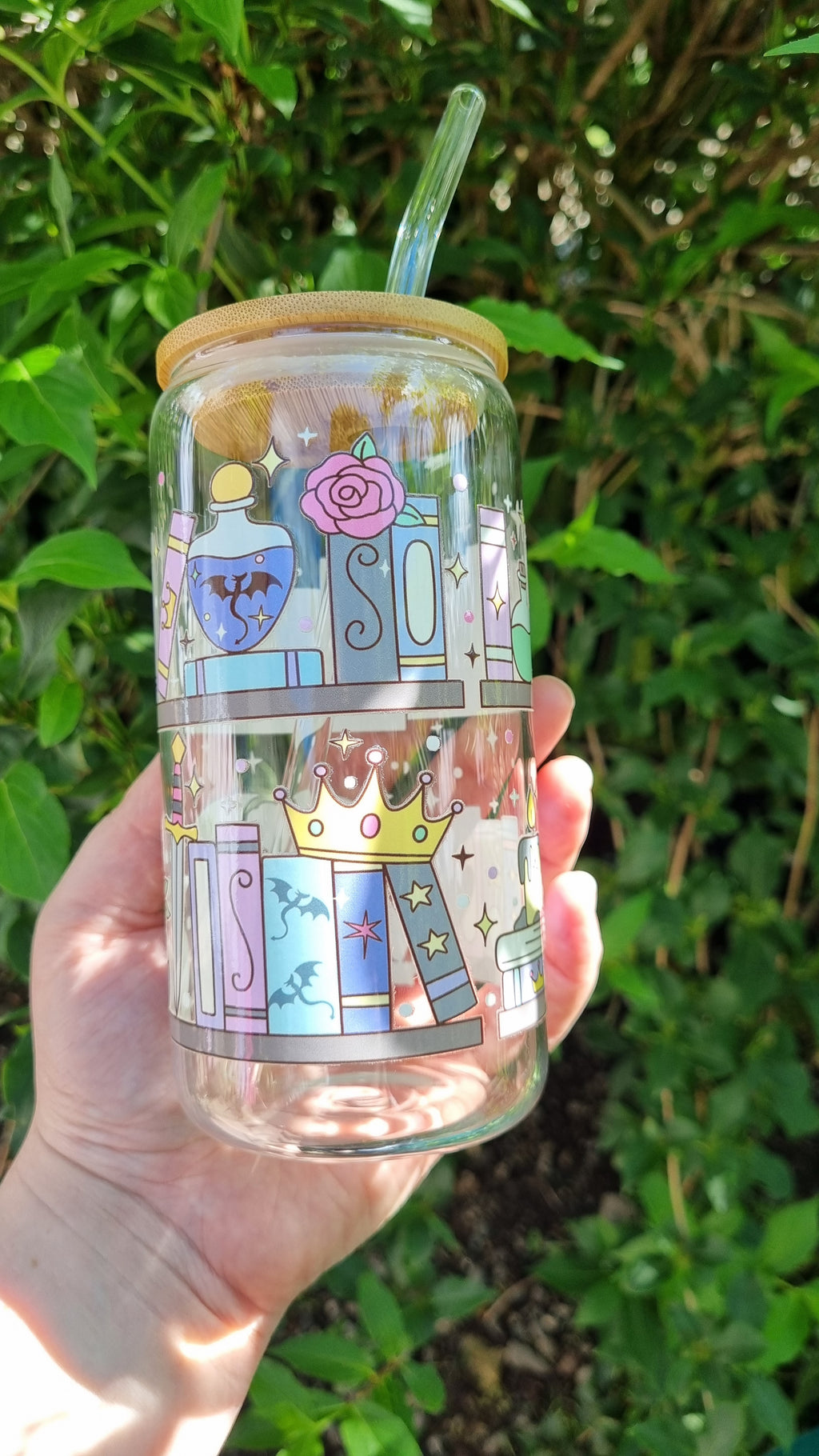 Sublimely Special fantasy bookshelf glass tumbler with straw and wooden lid held outdoors