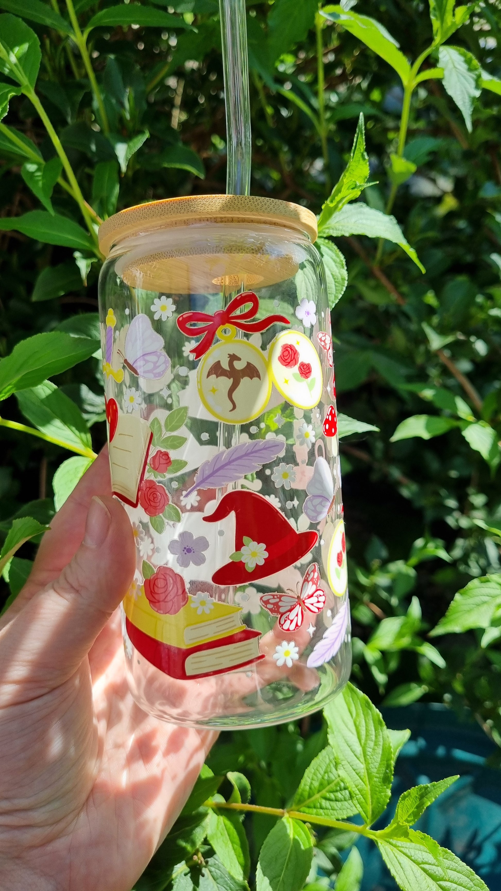 Clear tumbler with wooden lid and straw featuring fantasy romance bookish tumbler design with hats, books, and flowers