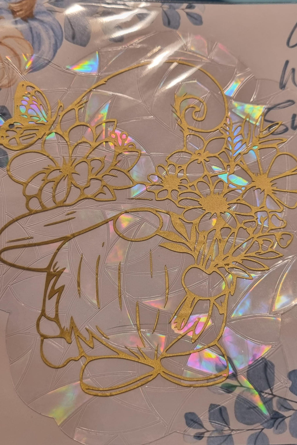 Gold gonk suncatcher with floral and butterfly design on iridescent background