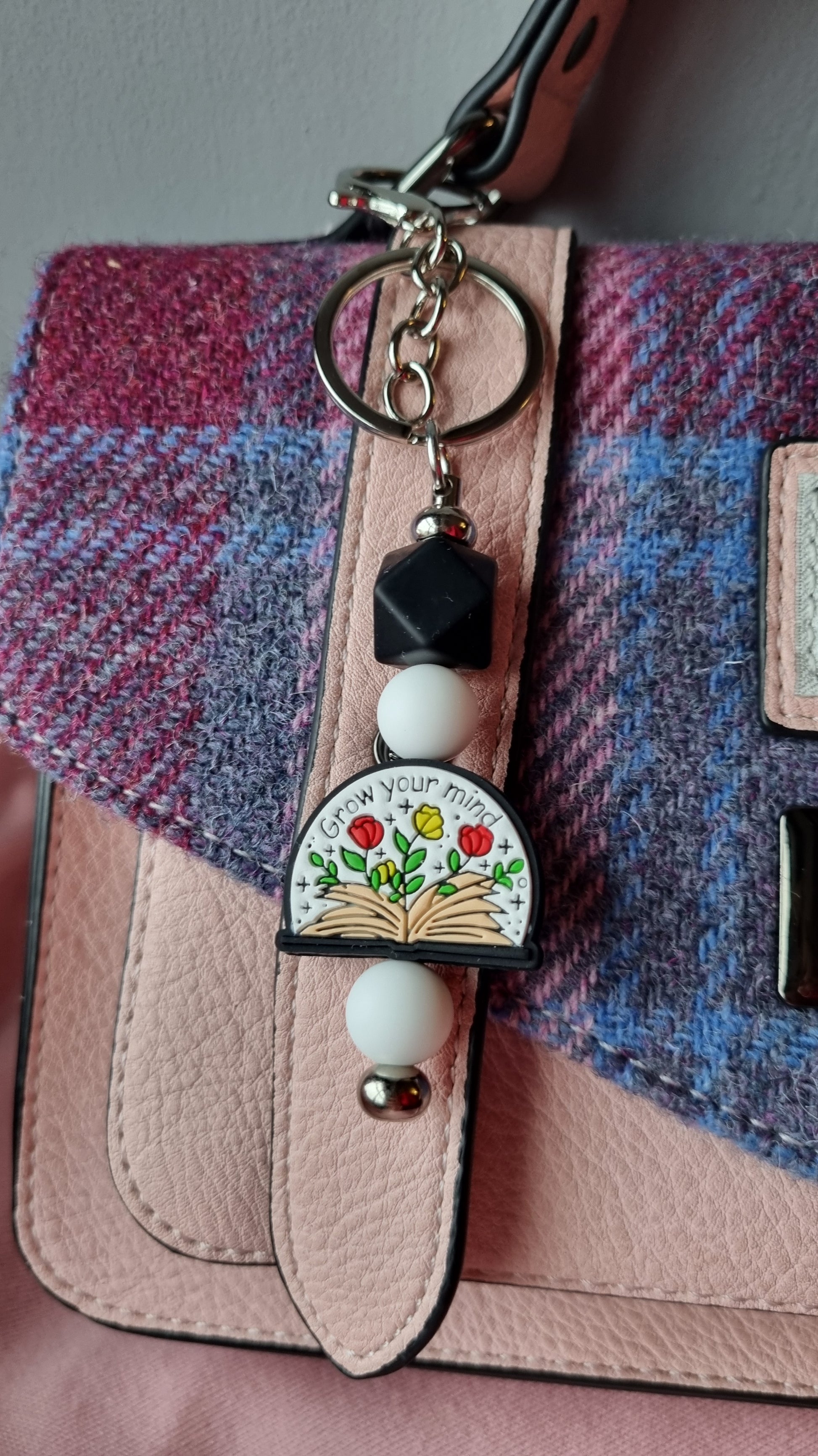 Sublimely Special grow your mind keychain with floral design hanging from a pink and purple textured bag