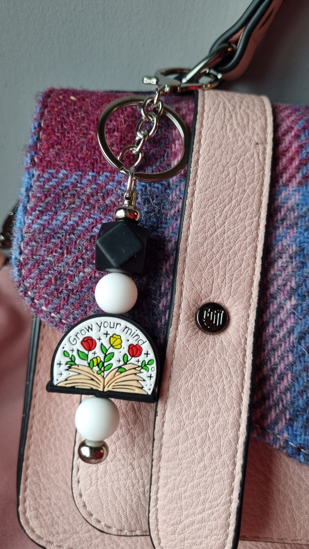 Sublimely Special grow your mind keychain with colourful flower and book design attached to pink and purple checkered bag