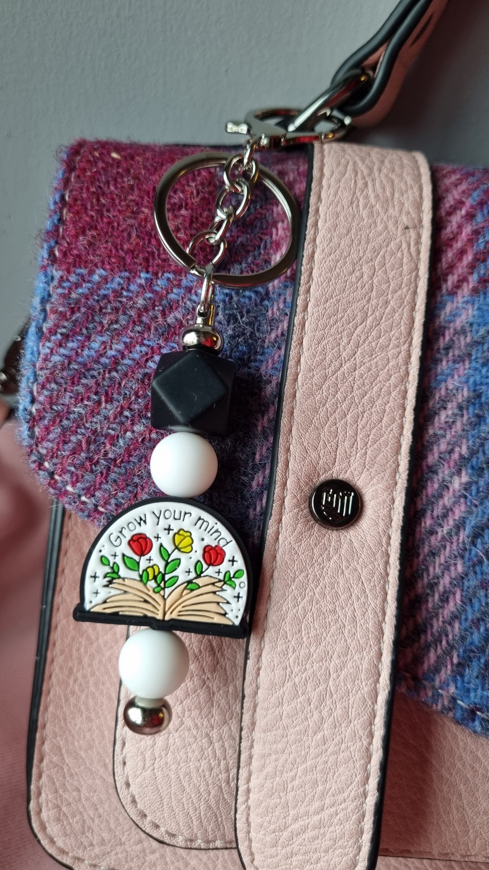 Sublimely Special grow your mind keychain with colourful flower and book design attached to pink and purple checkered bag