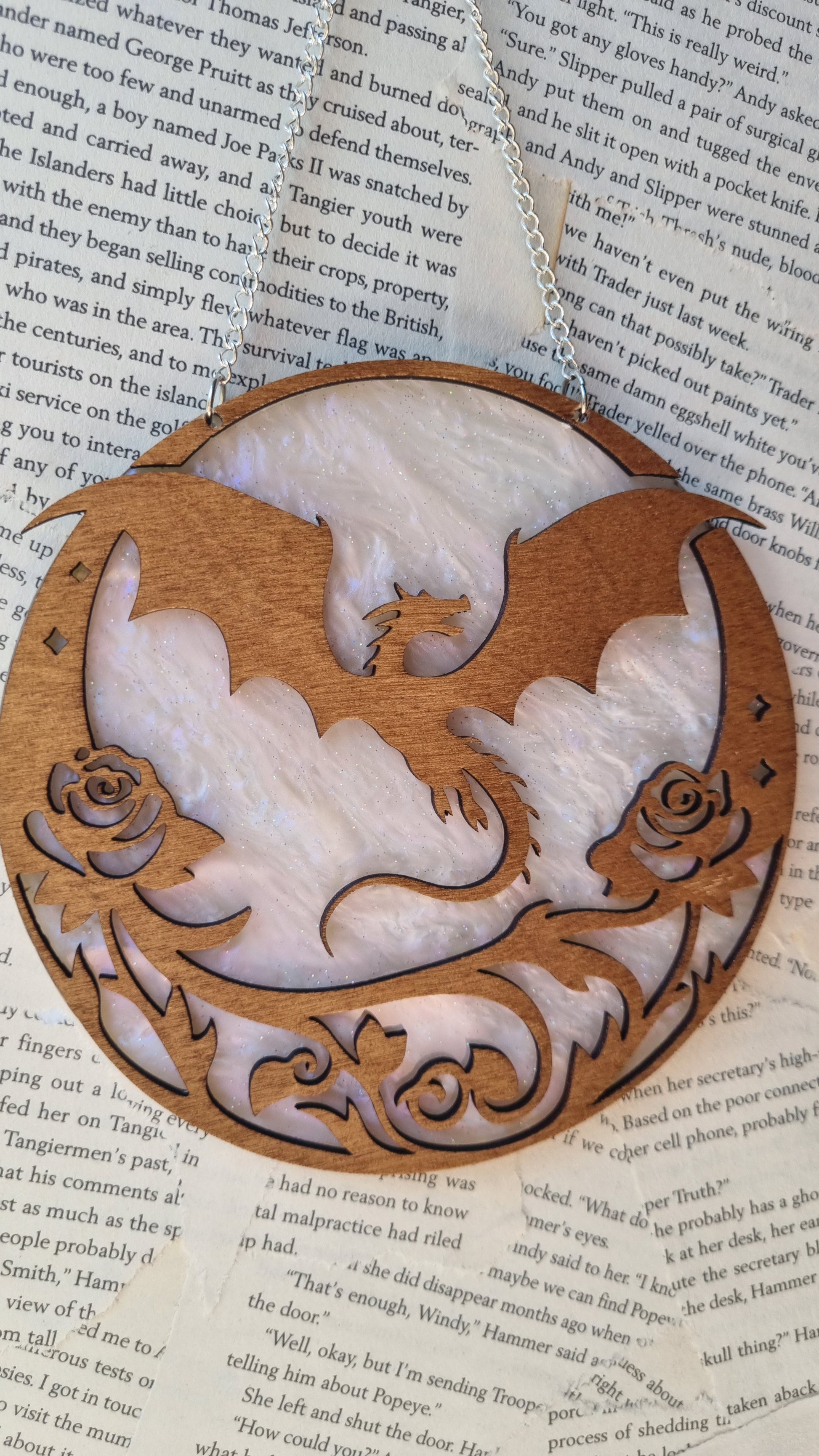 Whimsical dragon ornament for bookshelf made of intricately carved wood with floral details and hanging chain