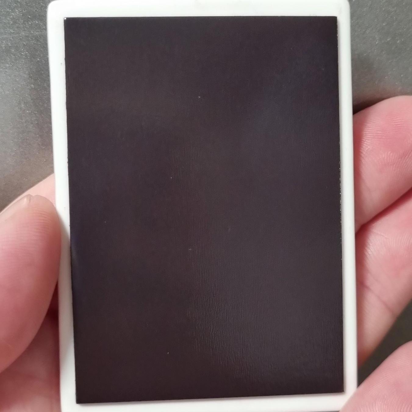 Hand holding the back of a highland cow fridge magnet with plain black magnetic surface