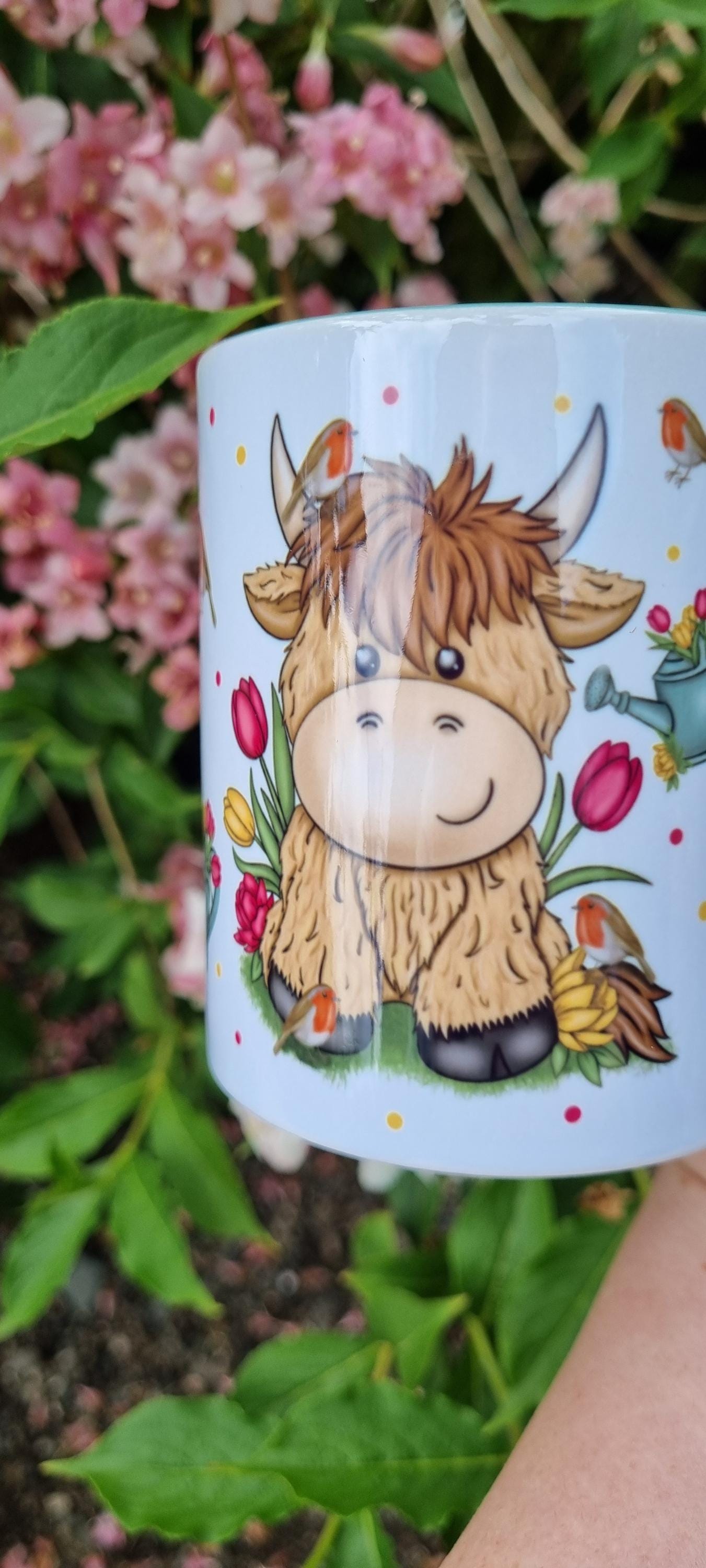 White mug featuring a cute cartoon highland cow with flowers perfect highland cow gift for animal lovers