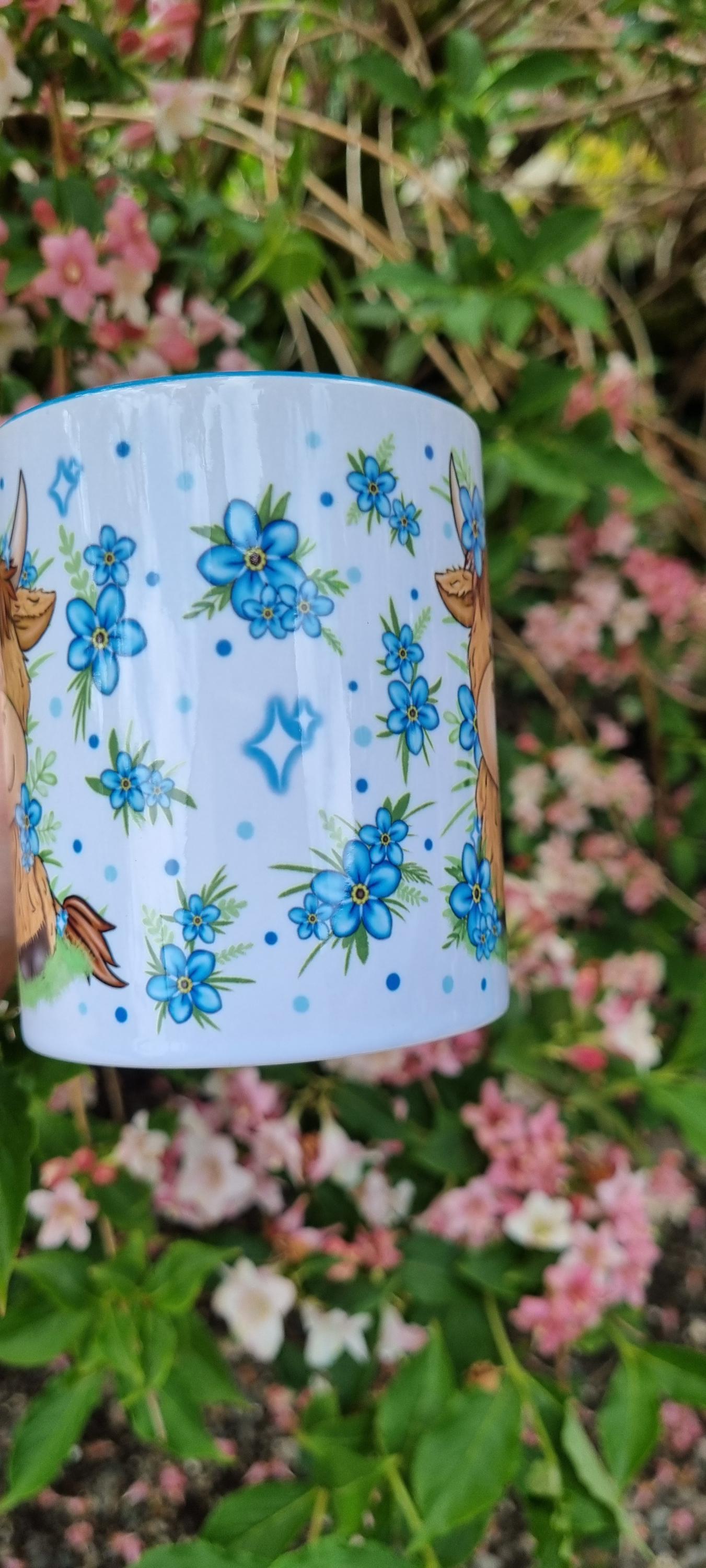 White mug decorated with blue flowers and highland cow illustrations, perfect highland cow gift for animal lovers