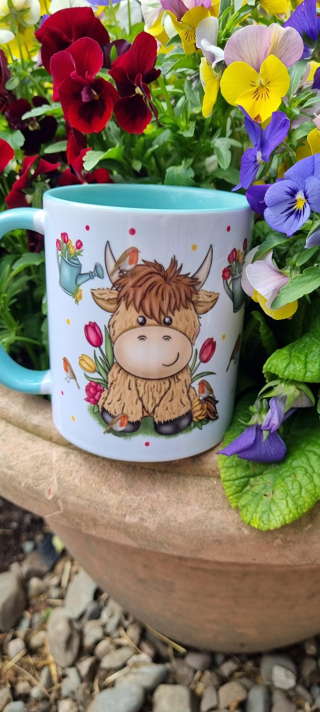 Cute ceramic mug with highland cow gift for animal lovers design surrounded by colourful garden flowers