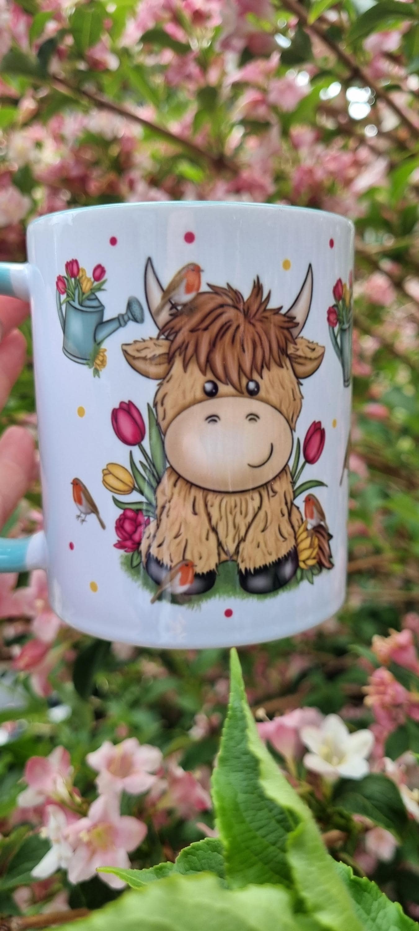 Cute cartoon highland cow mug surrounded by flowers featuring a watering can design highland cow gift for animal lovers
