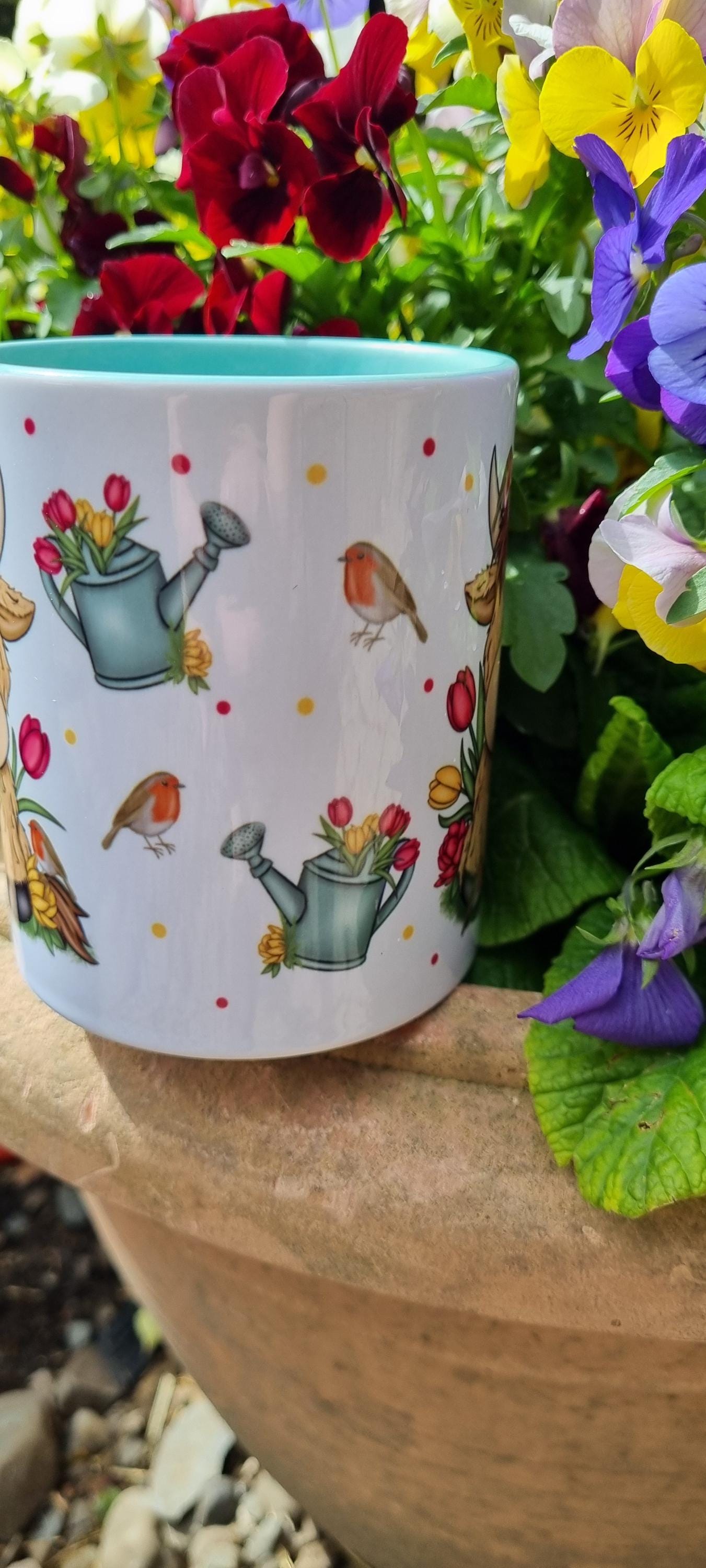 Ceramic mug with watering cans and robins design, perfect highland cow gift for animal lovers in garden setting