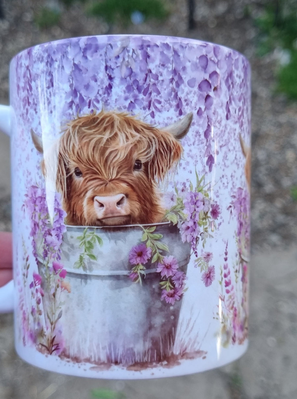 Ceramic highland cow mug featuring a cute cow peeking out of a bucket with purple flowers design