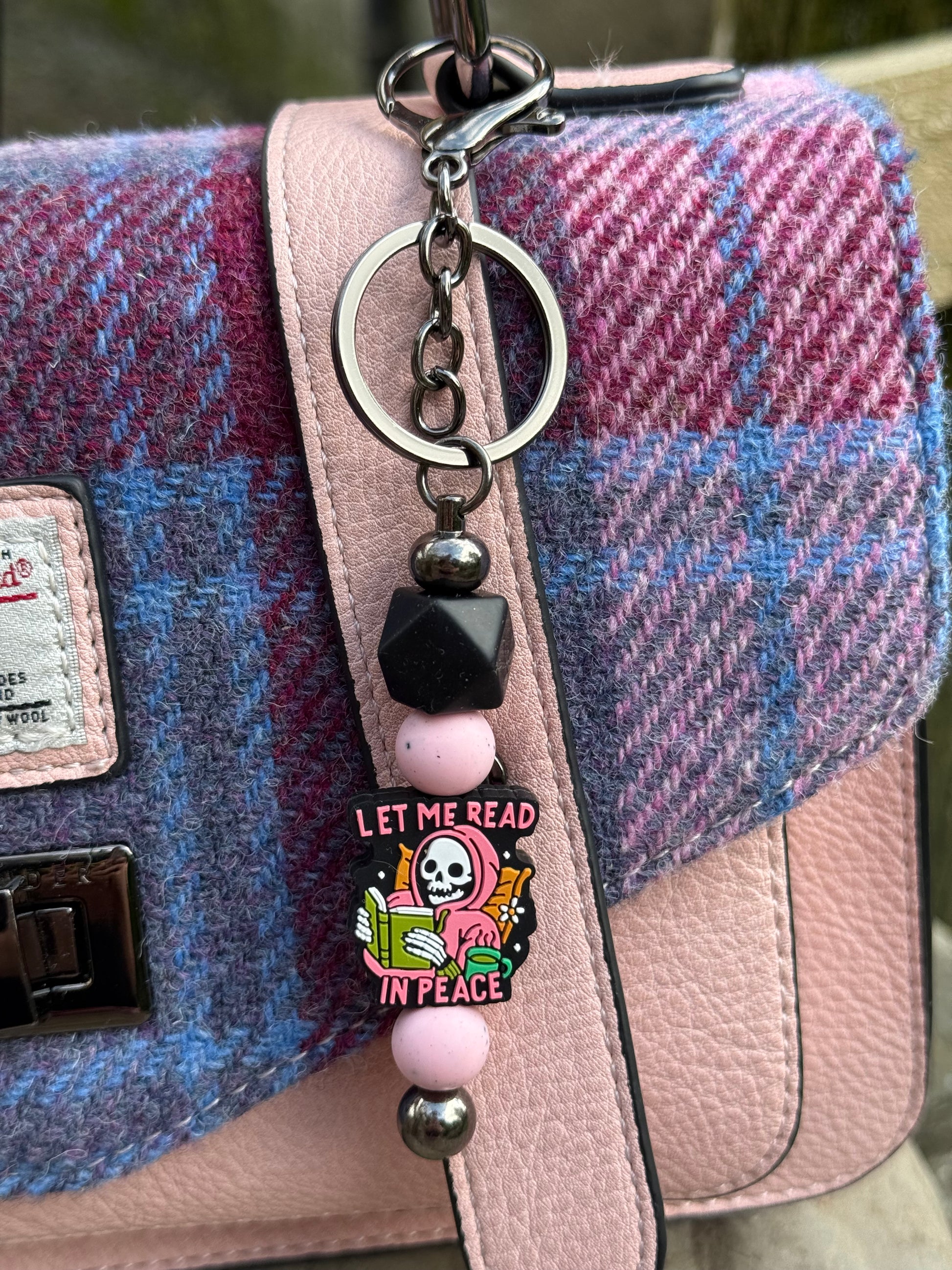 Sublimely Special let me read in peace keyring with skull and book charm hanging on pink and purple plaid handbag