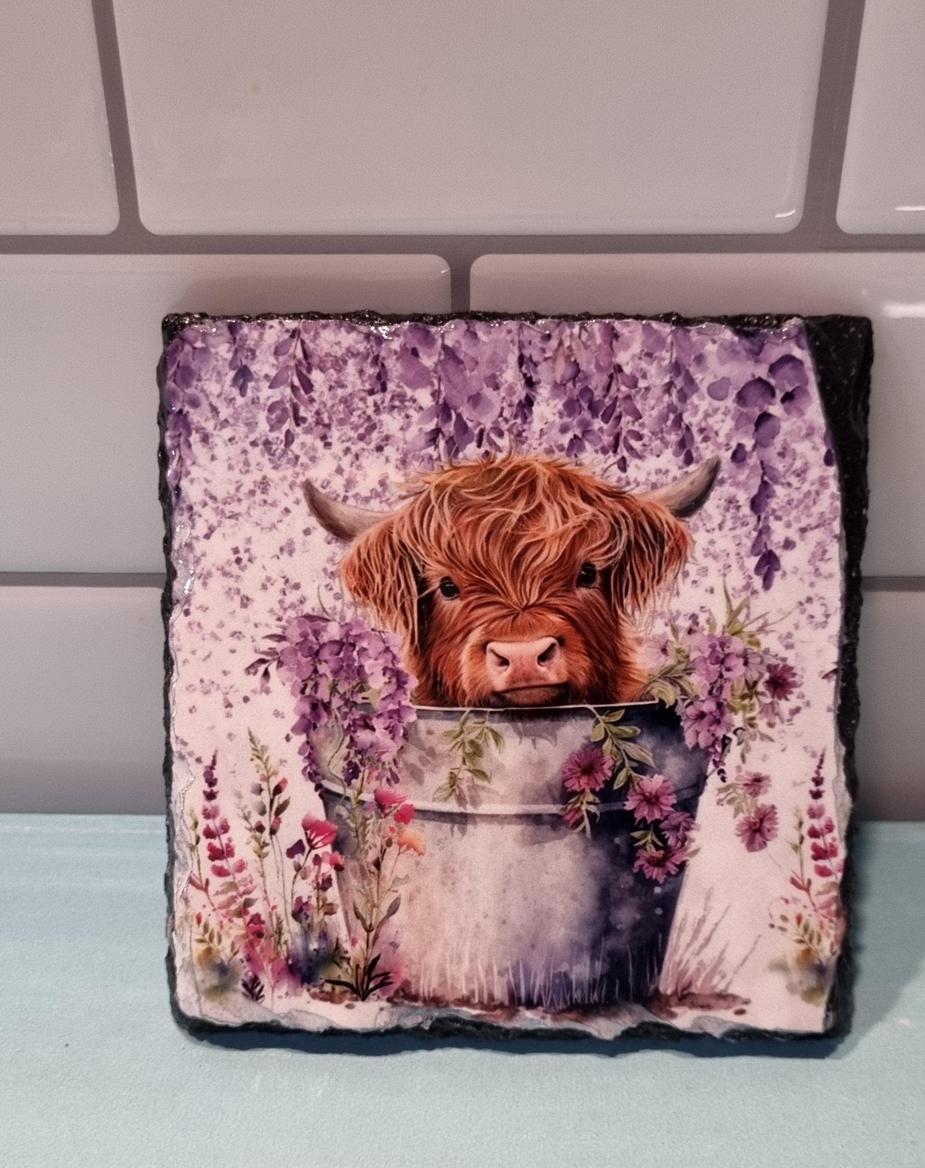 Lilac highland cow coaster featuring a cute highland cow peeking from a bucket with lilac flowers