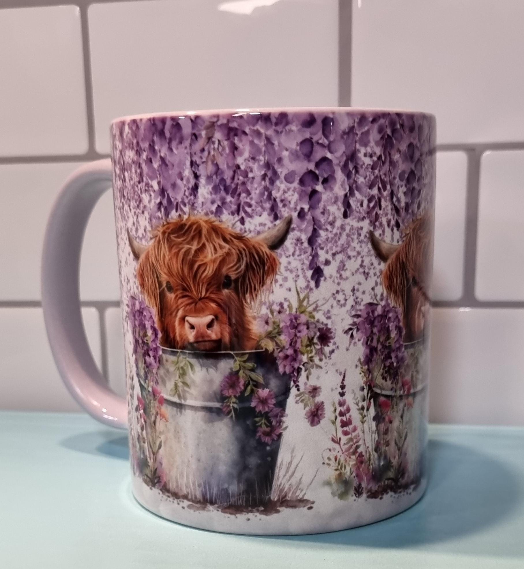 Ceramic lilac highland cow mug featuring a detailed illustration of a highland cow with lilac flowers