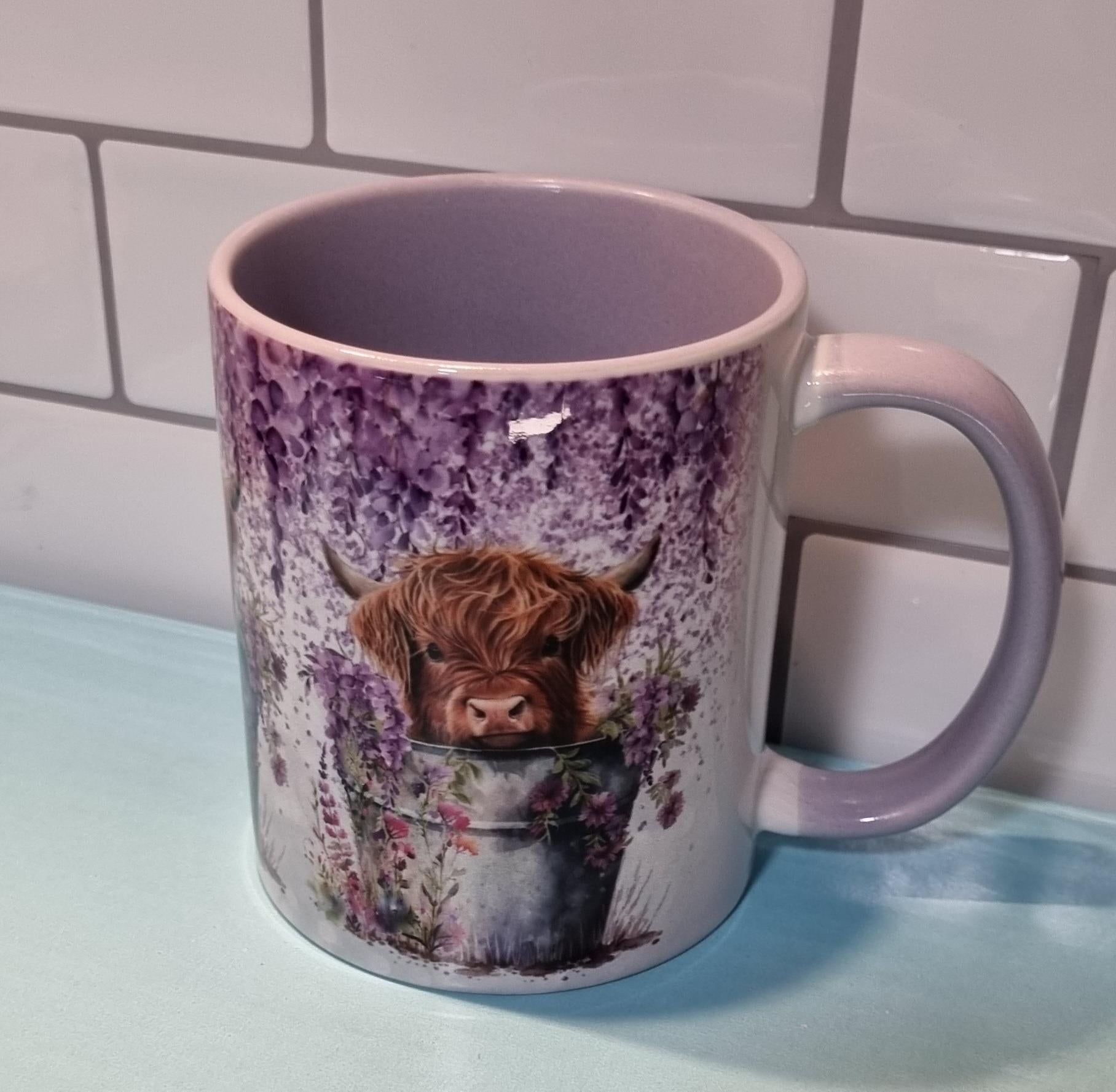 Lilac highland cow mug featuring a highland calf amidst purple flowers with a lilac handle