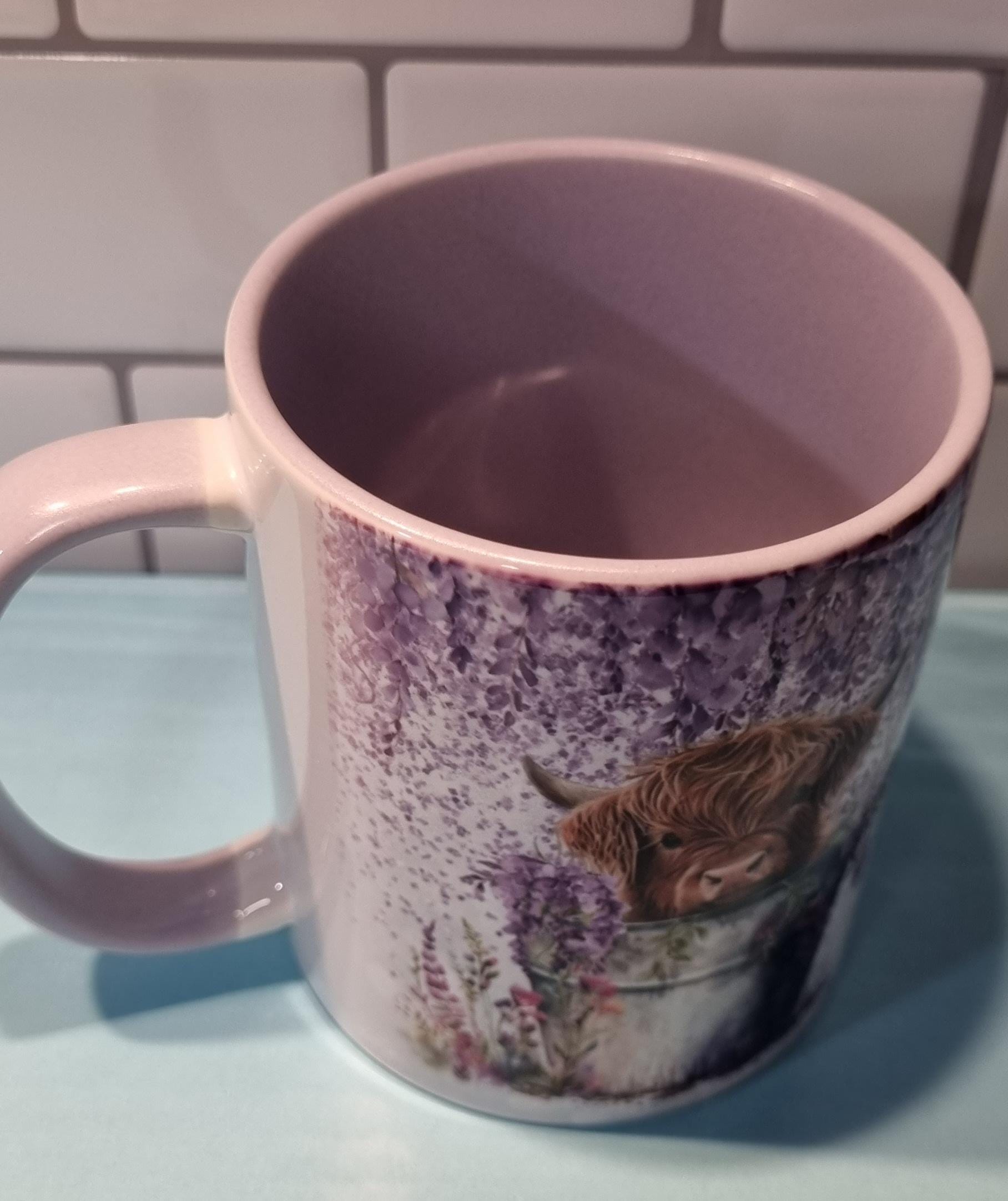 Ceramic lilac highland cow mug featuring a highland cow illustration with floral design and lilac interior
