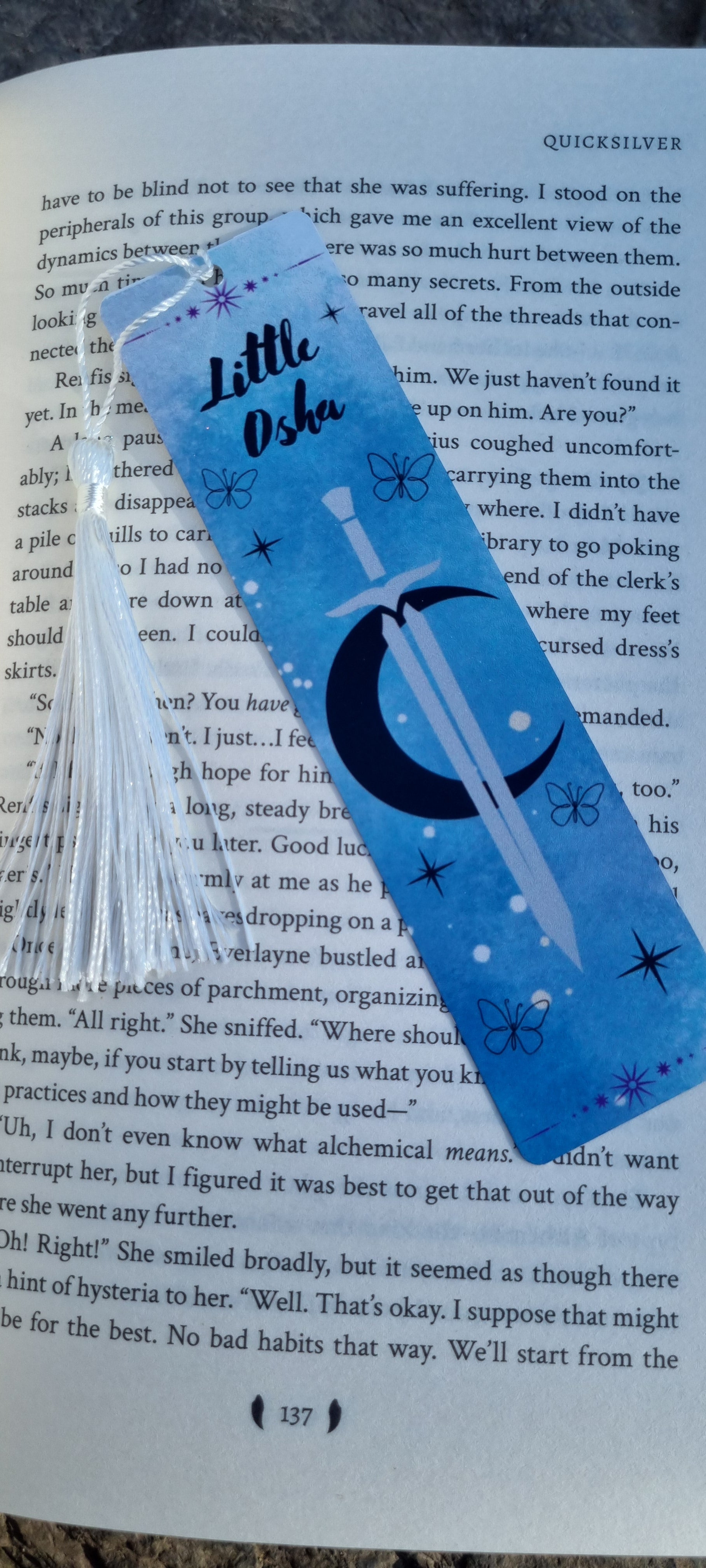 Blue fabric bookmark with white tassel featuring Little Osha book gift design and sword graphic