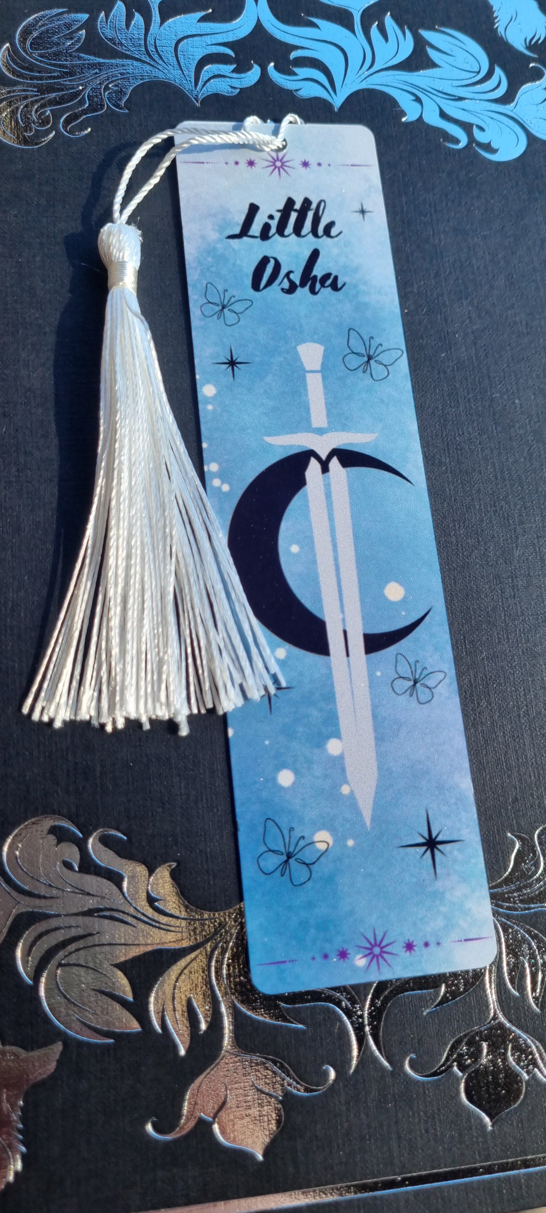 Little Osha book gift featuring a blue bookmark with a sword and crescent moon design by Sublimely Special