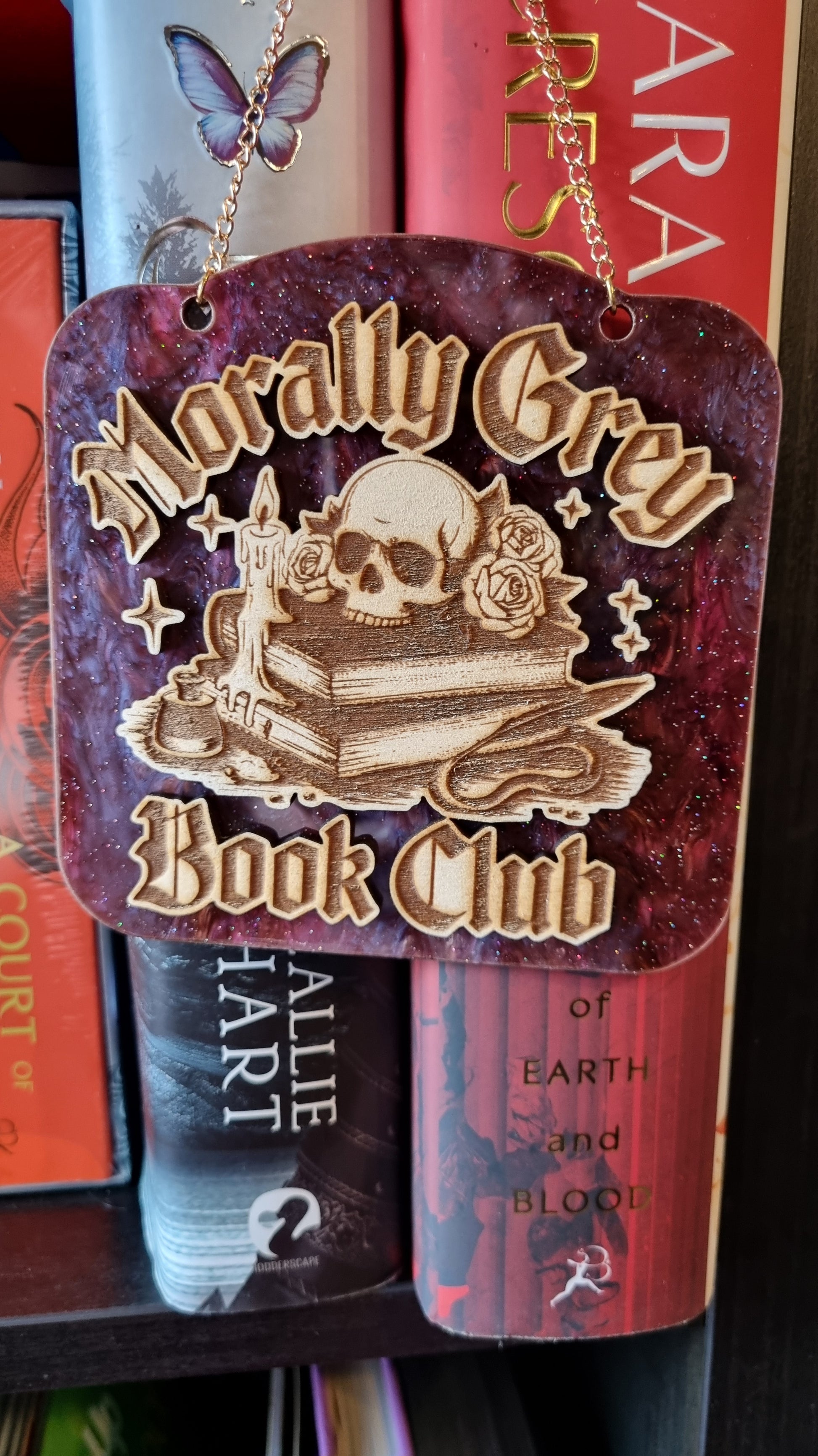 Morally grey book club ornament with skull and books design hanging in front of stacked books
