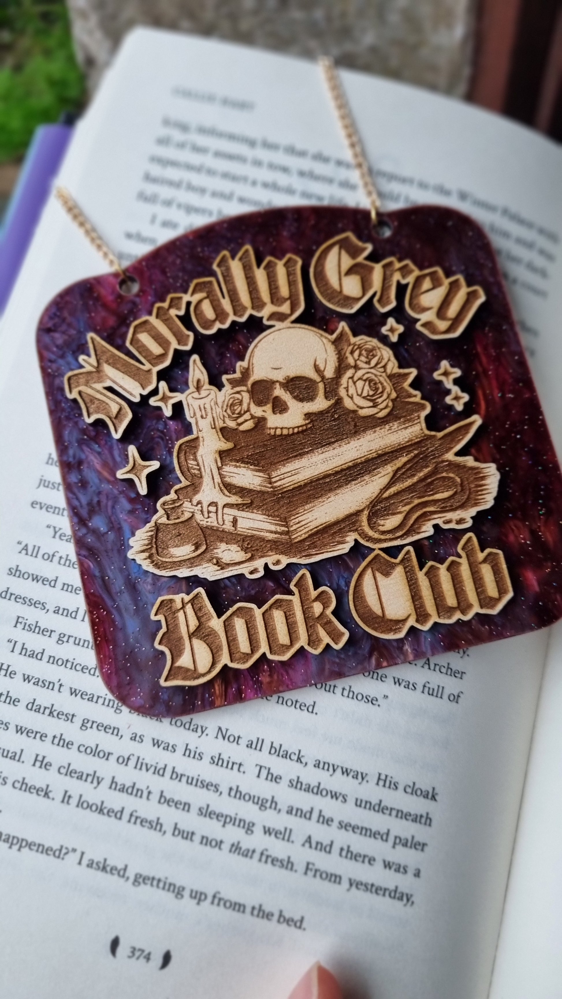 Morally grey book club ornament with skull and books design on a purple background hanging on an open book