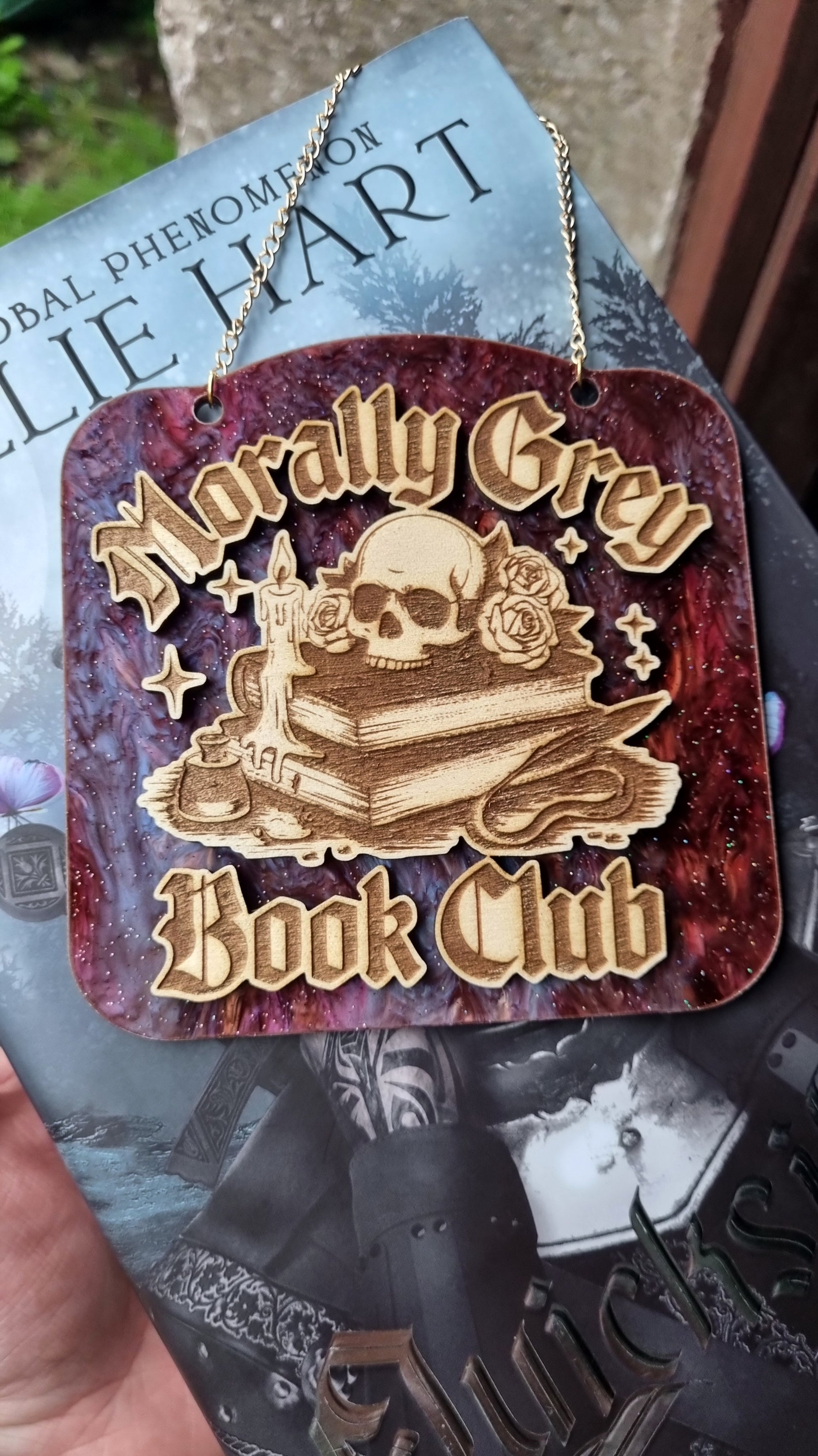 Morally grey book club ornament with skull and books design on maroon background hanging on chain