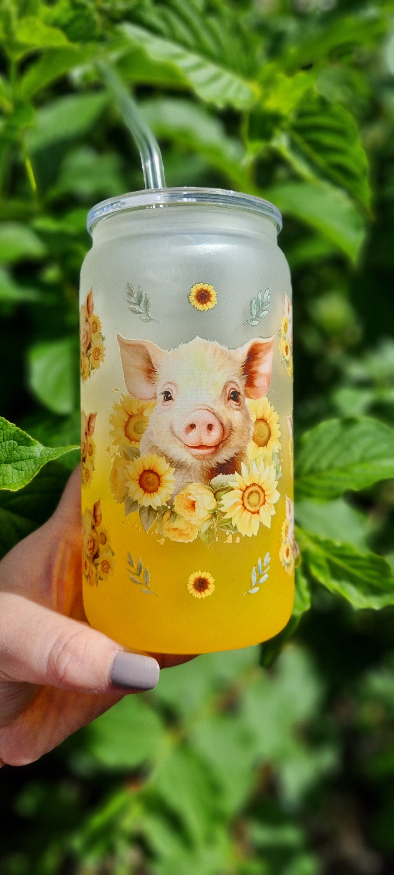 Pig sunflower glass tumbler with frosted design and bright yellow base held outdoors