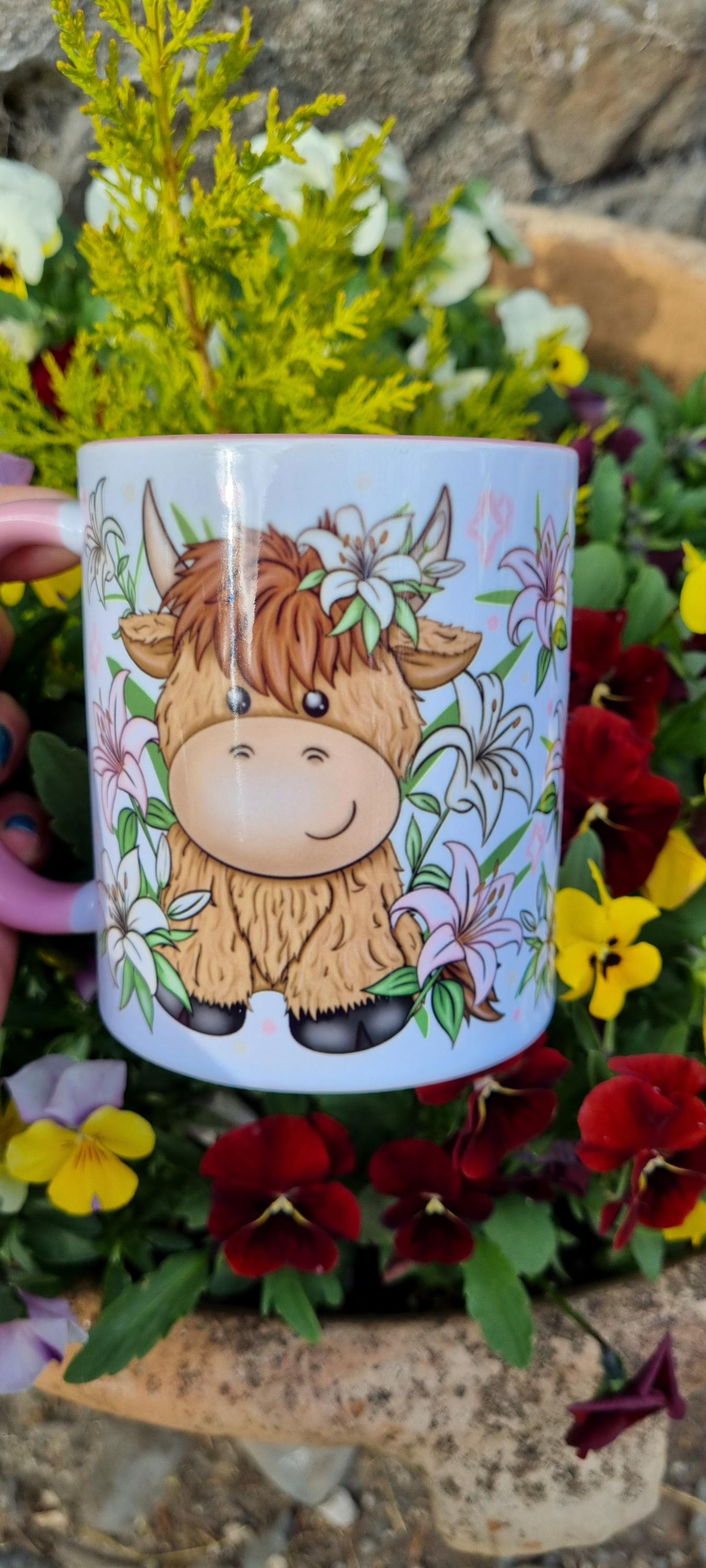 Cute pink highland cow mug with floral design featuring a smiling cartoon cow surrounded by flowers