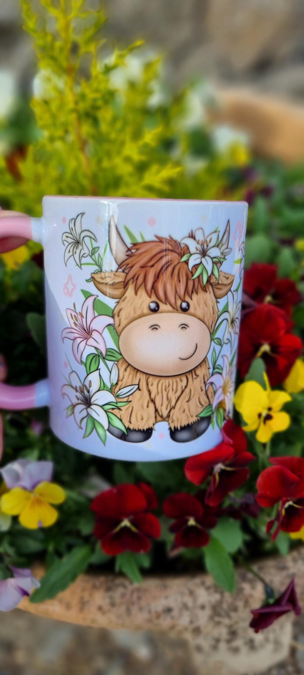 Pink highland cow mug with cute cartoon cow and floral design surrounded by garden flowers