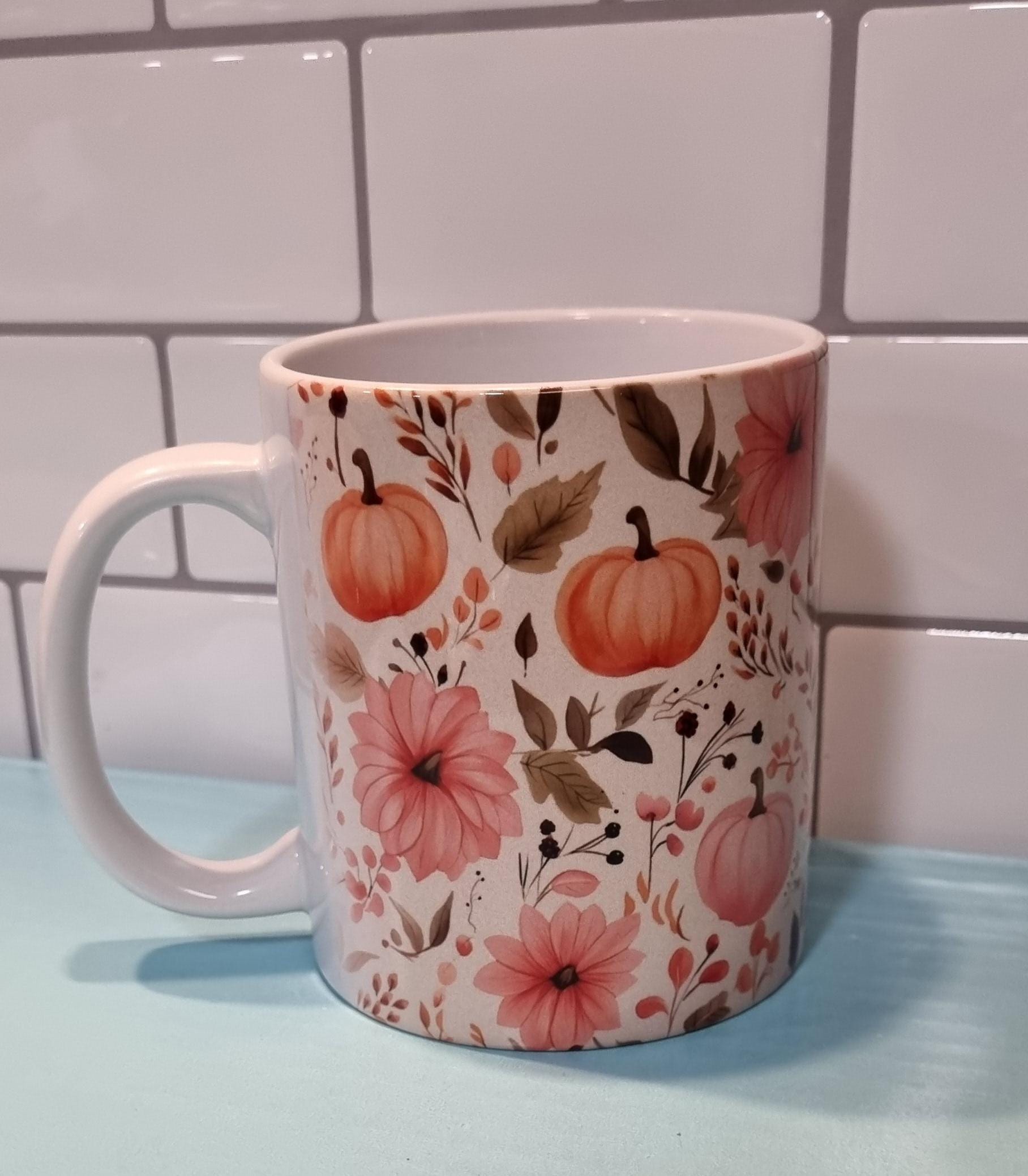 White ceramic pumpkin and flowers mug with orange pumpkins and pink floral design