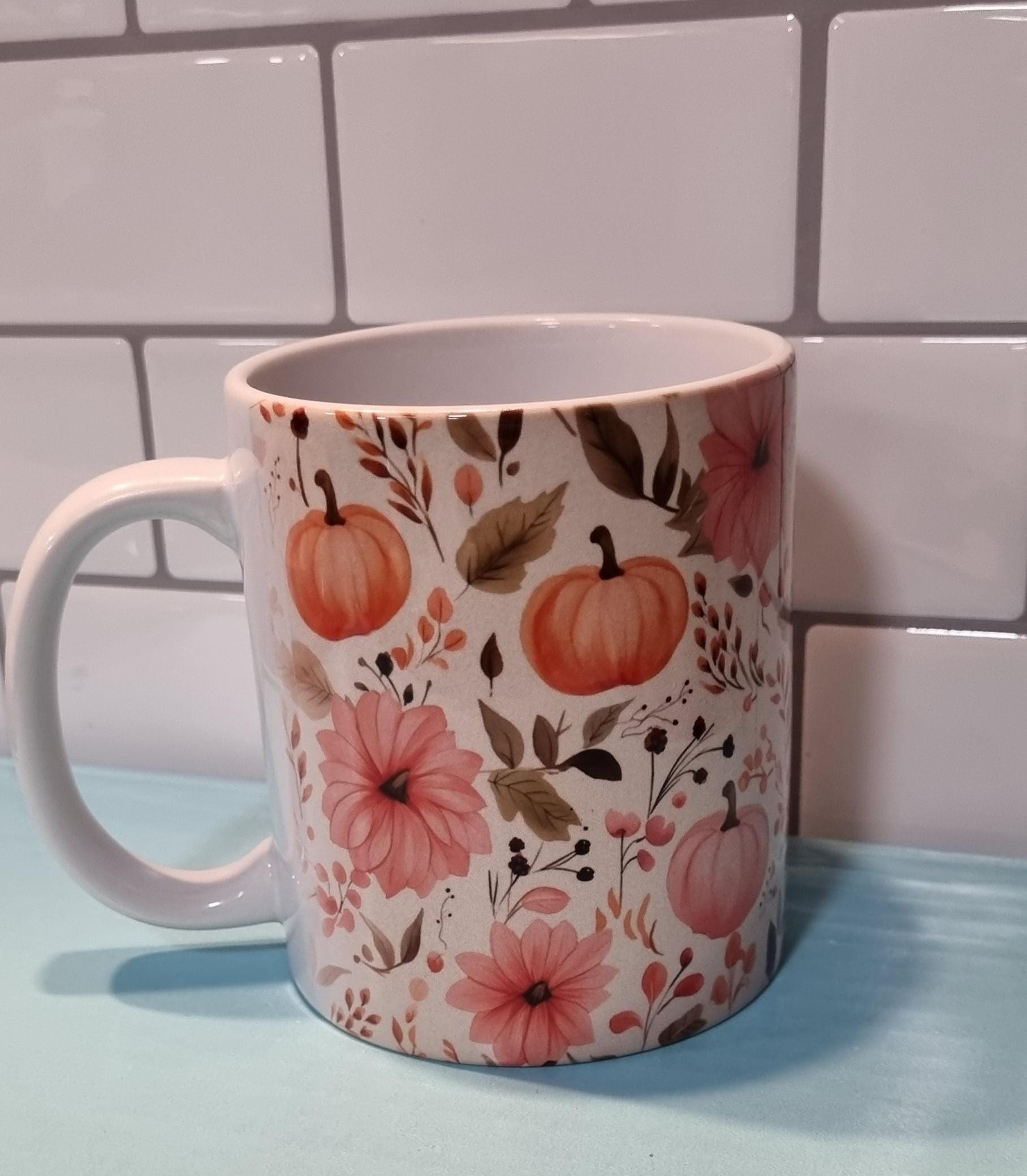 White ceramic pumpkin and flowers mug with autumnal orange pumpkins and pink floral design