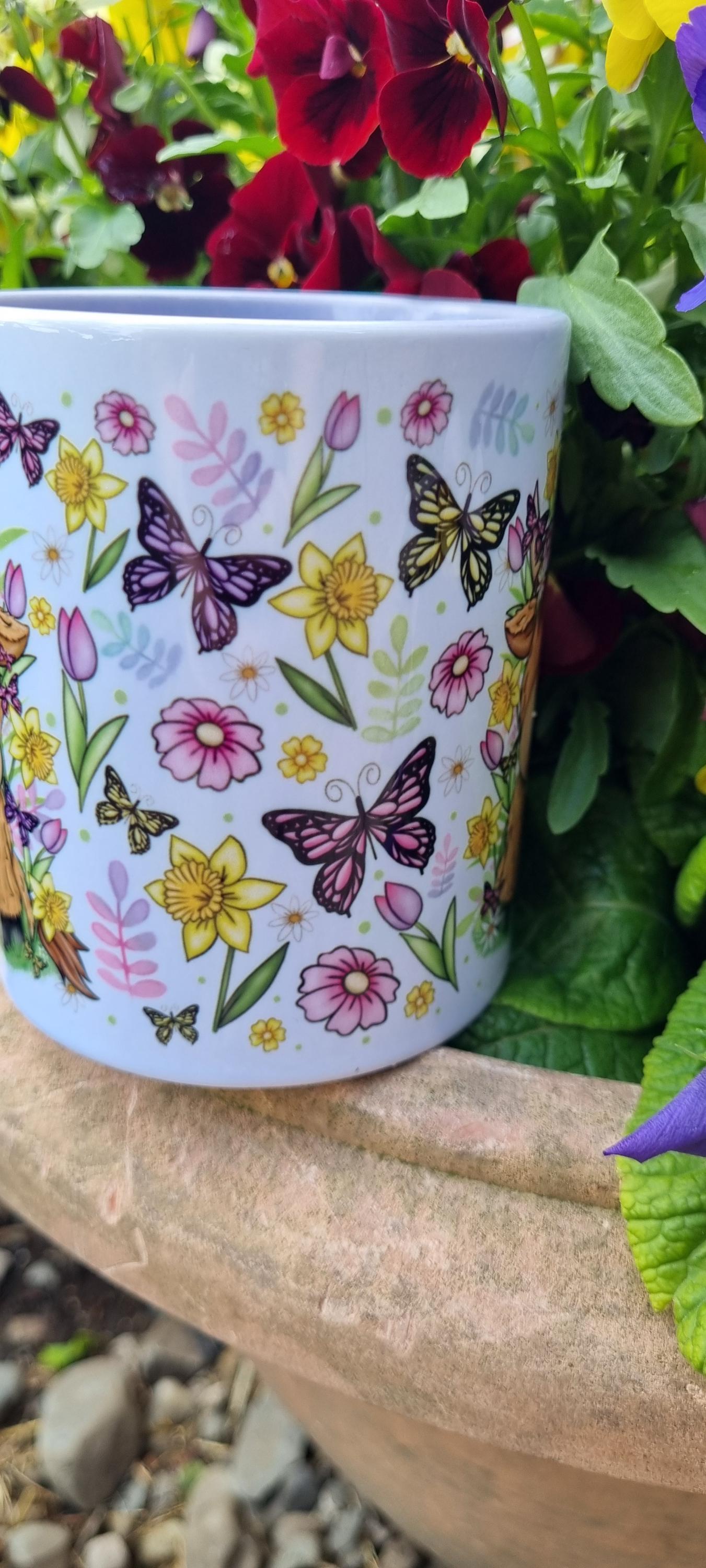 Spring cow coffee cup with colourful butterflies and flowers design placed outdoors among vibrant garden plants