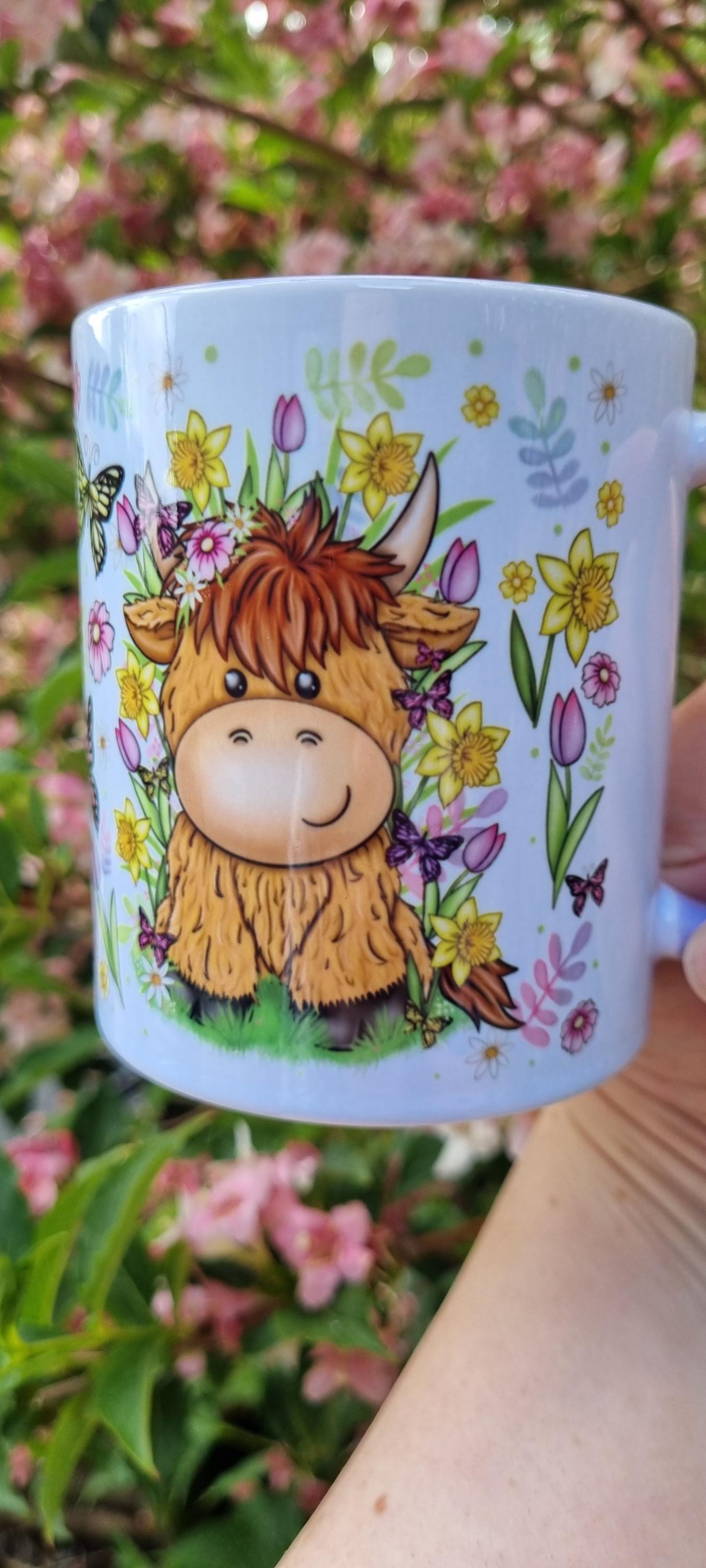 Spring cow coffee cup featuring a cute cartoon cow surrounded by colourful spring flowers and butterflies