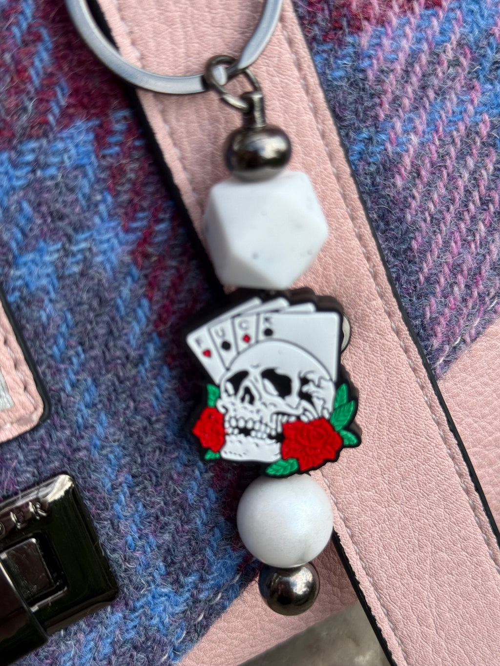 Morally grey fantasy book accessory keychain featuring a skull, playing cards, and red roses charm
