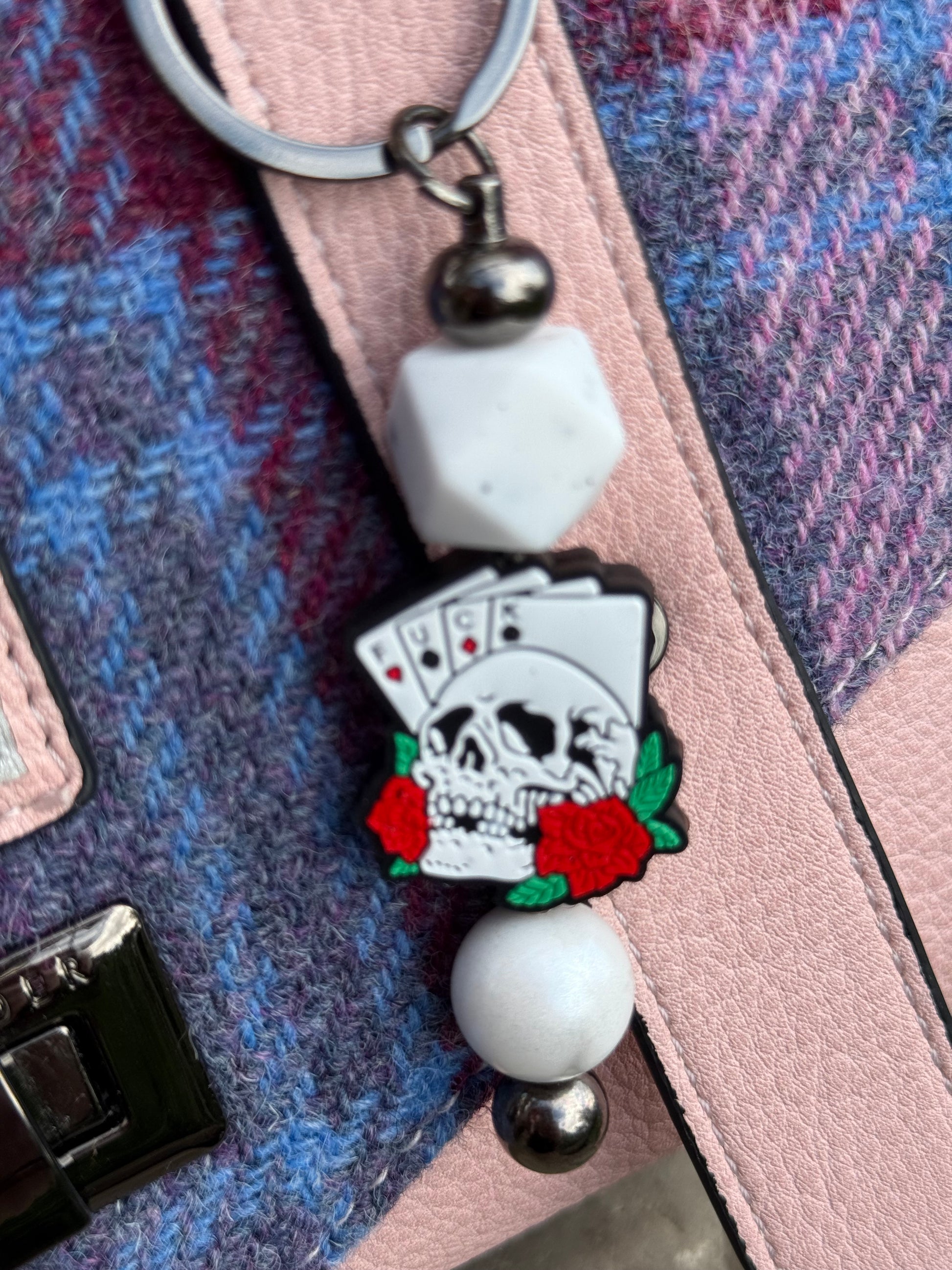 Morally grey fantasy book accessory keychain featuring a skull, playing cards, and red roses charm