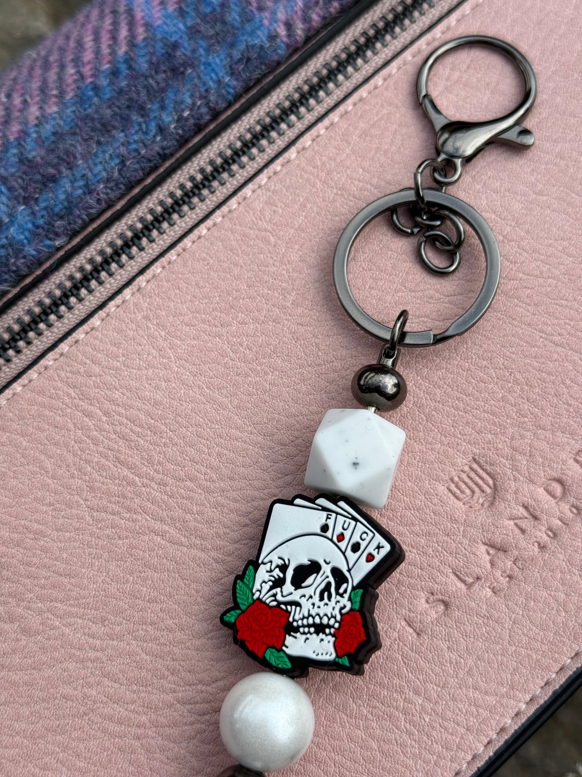 Morally grey fantasy book accessory keychain featuring a skull with playing cards and decorative beads