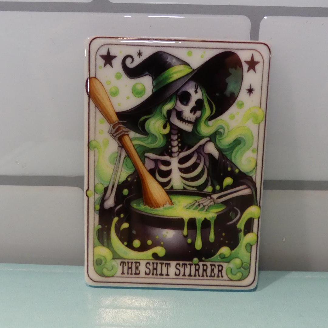 Witchy tarot fridge magnet featuring a skeleton witch stirring a bubbling green cauldron with text The Shit Stirrer